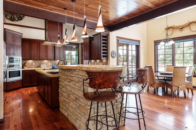 kitchen with stainless steel appliances, light countertops, a sink, and decorative light fixtures