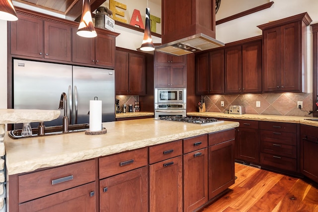 kitchen featuring decorative light fixtures, decorative backsplash, light wood-style floors, island range hood, and built in appliances