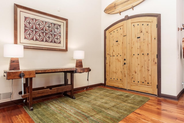 entryway featuring arched walkways, visible vents, baseboards, and wood finished floors