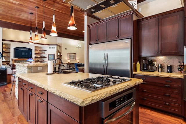 kitchen featuring wood finished floors, a sink, open floor plan, appliances with stainless steel finishes, and pendant lighting