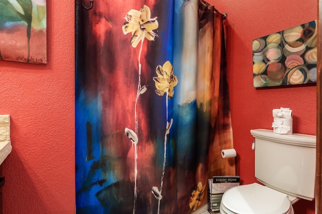 bathroom featuring a textured wall and toilet