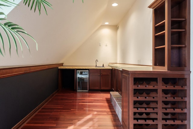 bar featuring beverage cooler, a sink, baseboards, dark wood-style floors, and indoor wet bar