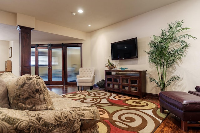 living area featuring french doors, recessed lighting, ornate columns, dark wood-type flooring, and baseboards