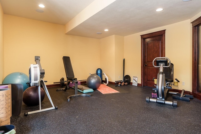 exercise room featuring baseboards, a textured ceiling, and recessed lighting