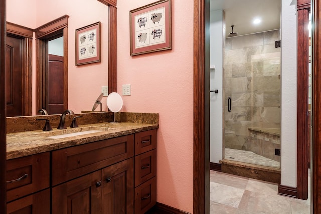 bathroom with a stall shower, vanity, and baseboards