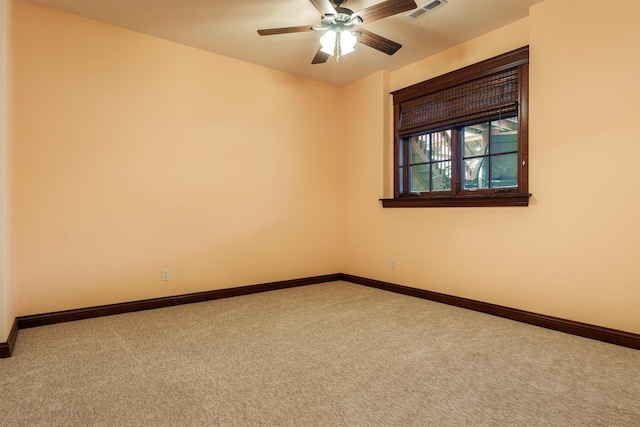 carpeted spare room featuring baseboards, visible vents, and ceiling fan