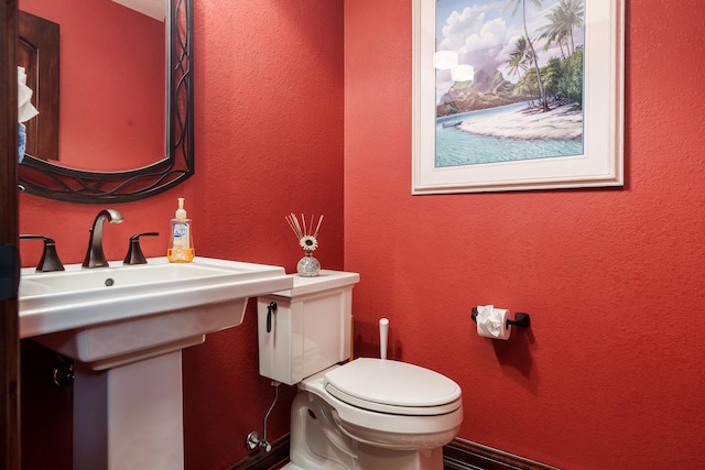 half bath featuring a textured wall and toilet