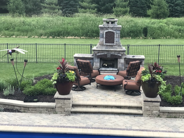 view of patio featuring fence and an outdoor stone fireplace