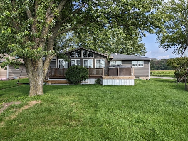 back of house with a deck, a yard, and a hot tub