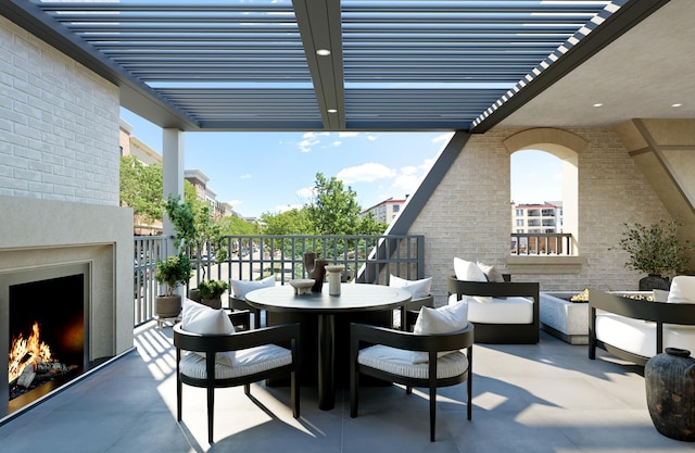 view of patio with a warm lit fireplace, outdoor dining area, a balcony, and a pergola