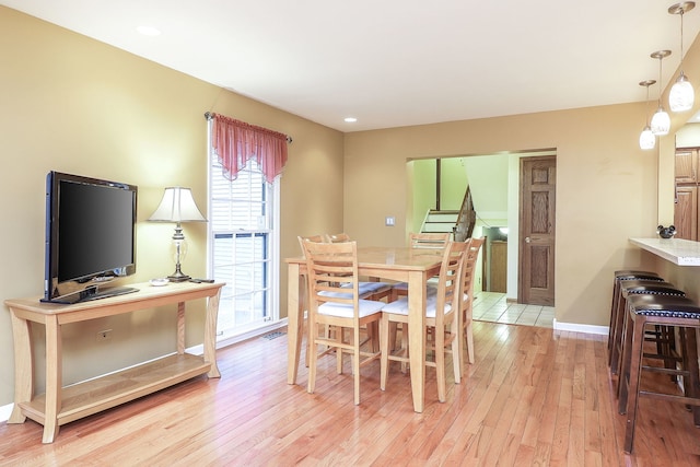 dining area with light wood finished floors, stairs, baseboards, and recessed lighting