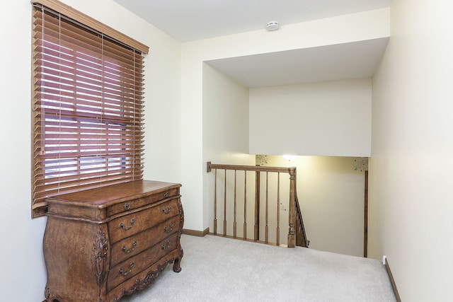 hall featuring carpet, baseboards, and an upstairs landing