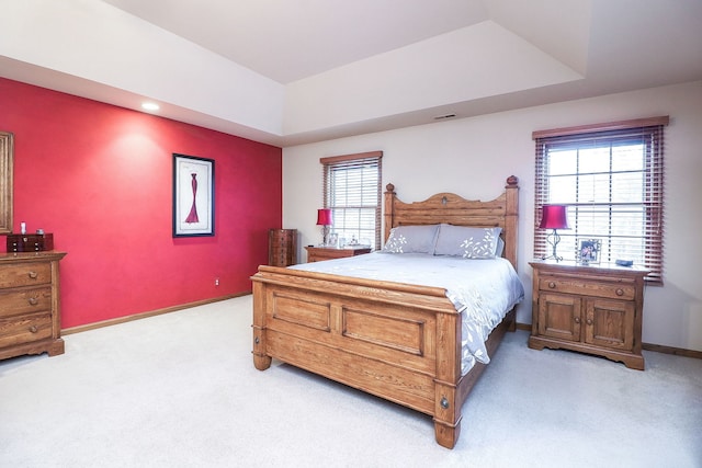 bedroom featuring light carpet, baseboards, visible vents, and a tray ceiling