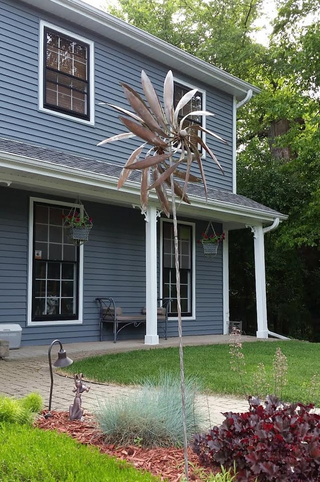 back of house with a porch and roof with shingles