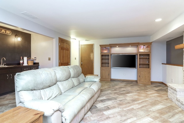 living room with light wood-type flooring, baseboards, and visible vents