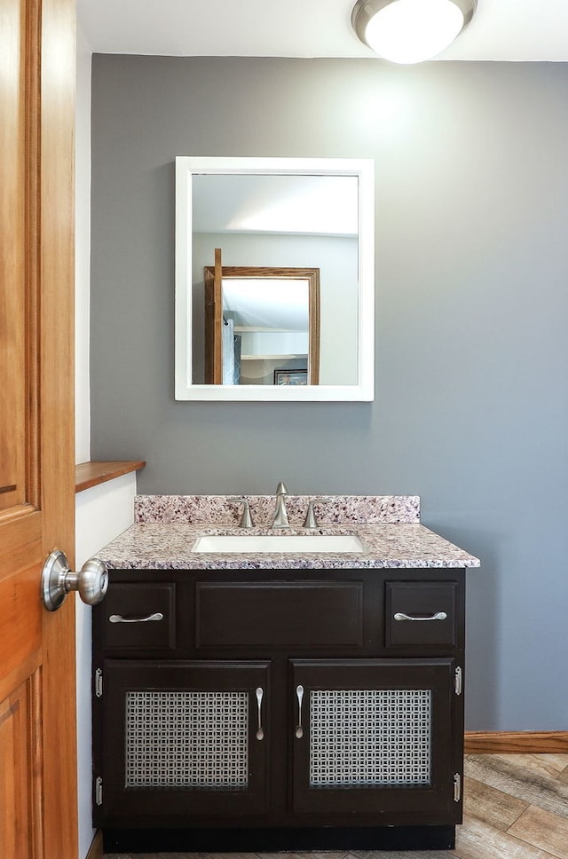 bathroom with wood finished floors, vanity, and baseboards