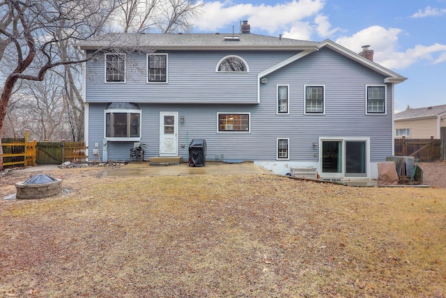 rear view of property featuring a fenced backyard, a patio, a fire pit, and a lawn