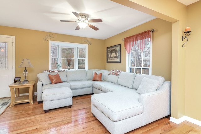 living area with a healthy amount of sunlight, ceiling fan, light wood-style flooring, and baseboards