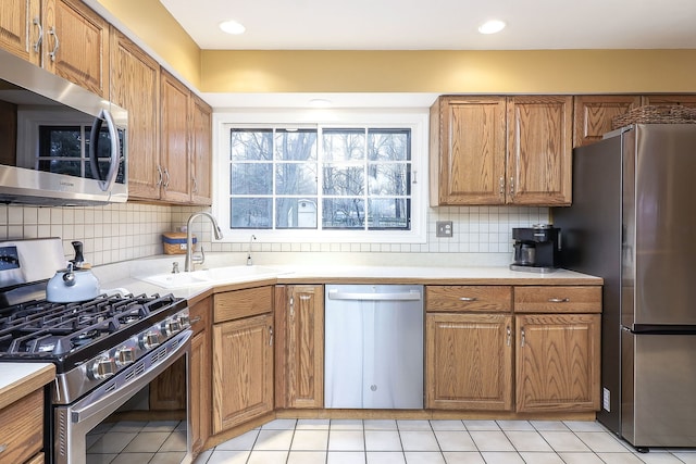 kitchen featuring stainless steel appliances, brown cabinets, a sink, and decorative backsplash