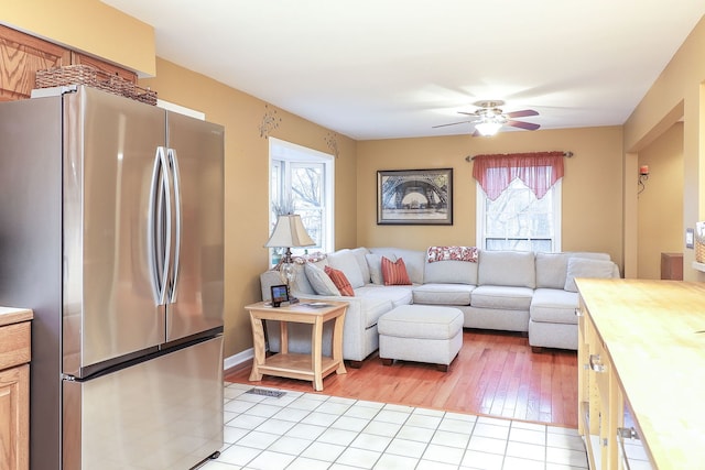 living area featuring light wood-style floors, plenty of natural light, and ceiling fan