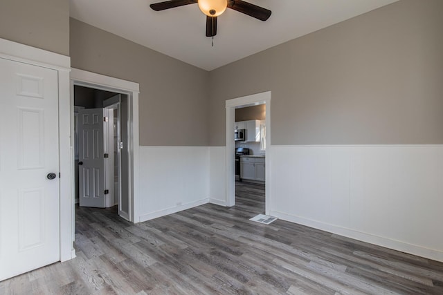 1503 Ottawa Ave, Ottawa, IL 61350 - empty room with light wood-type flooring, visible vents, a ceiling fan, and wainscoting