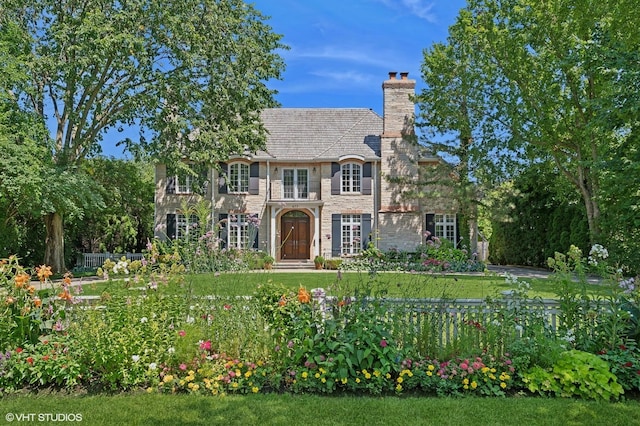 view of front of home with stone siding, a chimney, and a front yard