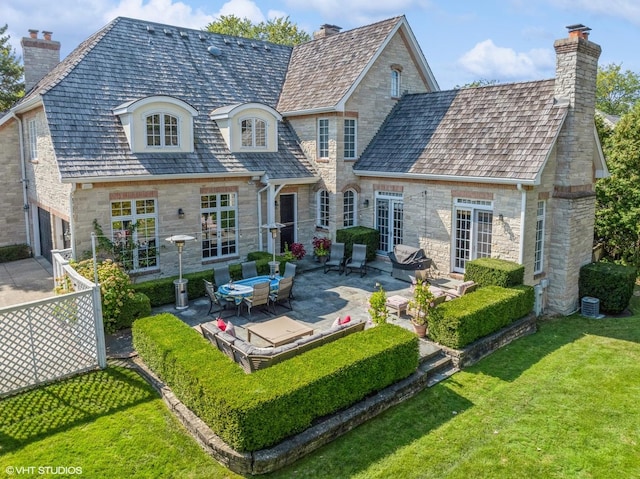 rear view of property featuring stone siding, a chimney, a patio, and french doors