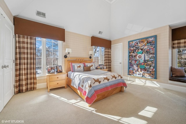 bedroom featuring high vaulted ceiling, light colored carpet, visible vents, and wallpapered walls