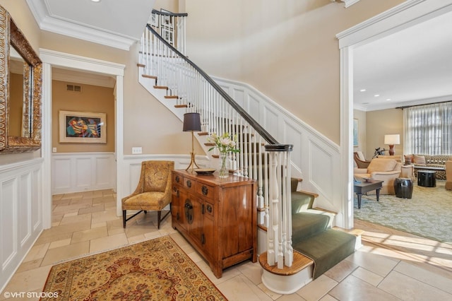 stairs featuring visible vents, ornamental molding, a decorative wall, and stone tile flooring