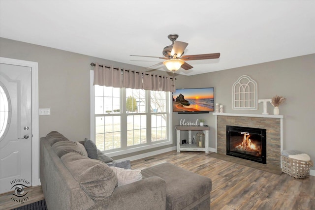 living room with ceiling fan, wood finished floors, and a glass covered fireplace