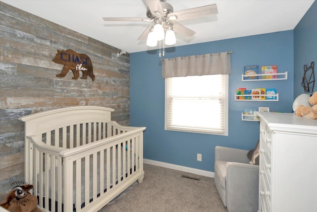 bedroom with visible vents, light colored carpet, an accent wall, a crib, and baseboards