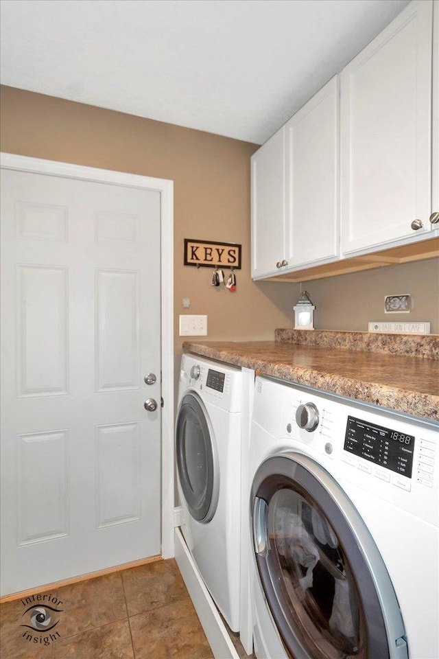 clothes washing area featuring washer and clothes dryer, light tile patterned flooring, and cabinet space