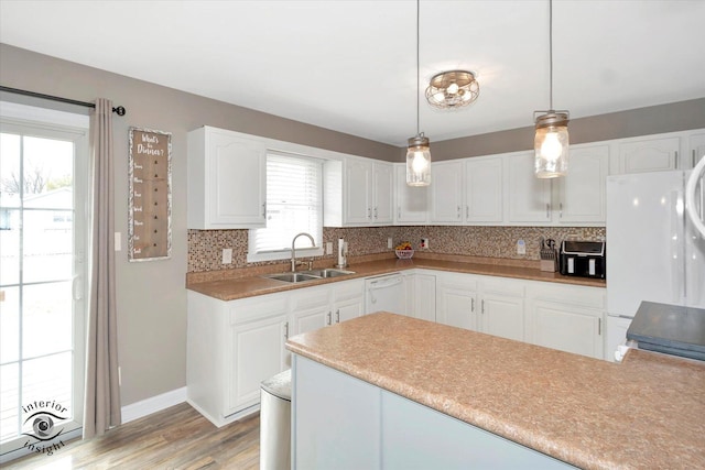 kitchen with light countertops, white cabinetry, a sink, and decorative light fixtures