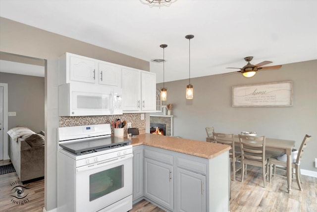 kitchen featuring white appliances, white cabinets, light countertops, hanging light fixtures, and decorative backsplash