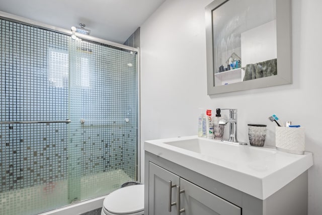 bathroom featuring toilet, a shower stall, and vanity
