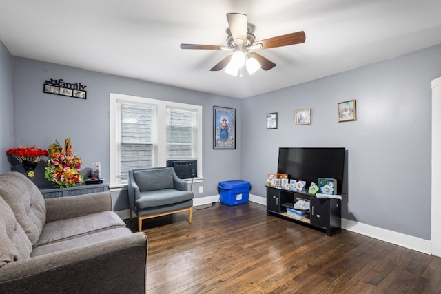 living area with a ceiling fan, dark wood finished floors, and baseboards