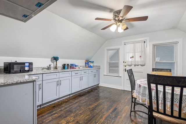 kitchen featuring ceiling fan, light stone counters, dark wood-type flooring, vaulted ceiling, and black microwave