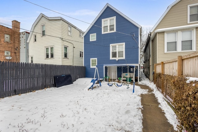 snow covered house with a fenced backyard