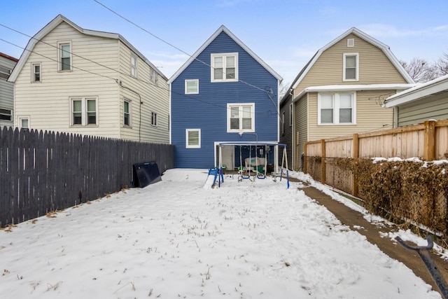 snow covered rear of property with a fenced backyard and a gambrel roof