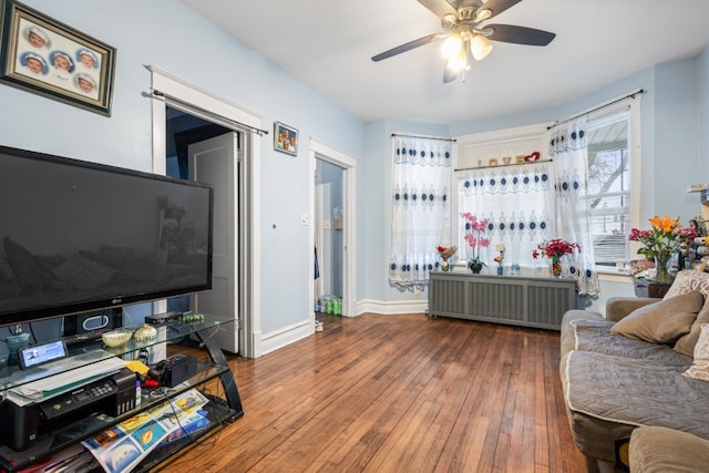 living room with a ceiling fan, radiator, baseboards, and wood finished floors