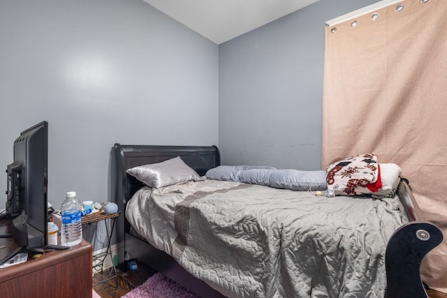 bedroom featuring dark wood-style flooring and vaulted ceiling