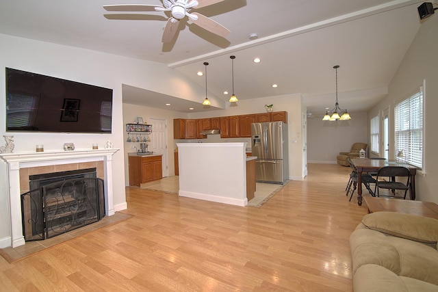 living room with lofted ceiling, baseboards, light wood-style flooring, and a tiled fireplace