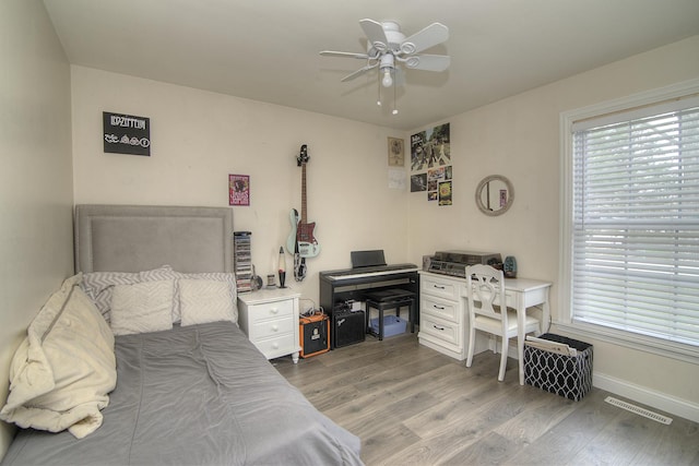 bedroom featuring a ceiling fan, visible vents, baseboards, and wood finished floors