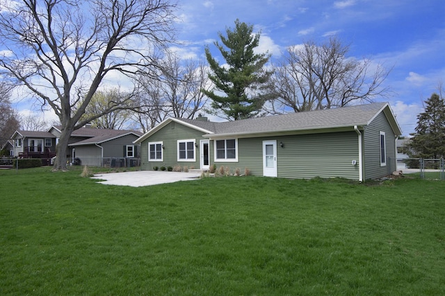 rear view of house with a patio area, a chimney, fence, and a lawn