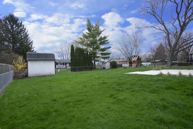 view of yard with a playground, an outdoor structure, a fenced backyard, and a shed