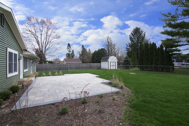 view of yard with an outbuilding, a shed, a patio area, and a fenced backyard