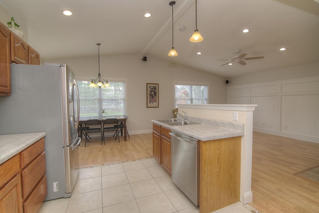 kitchen with appliances with stainless steel finishes, brown cabinetry, a sink, and lofted ceiling with beams