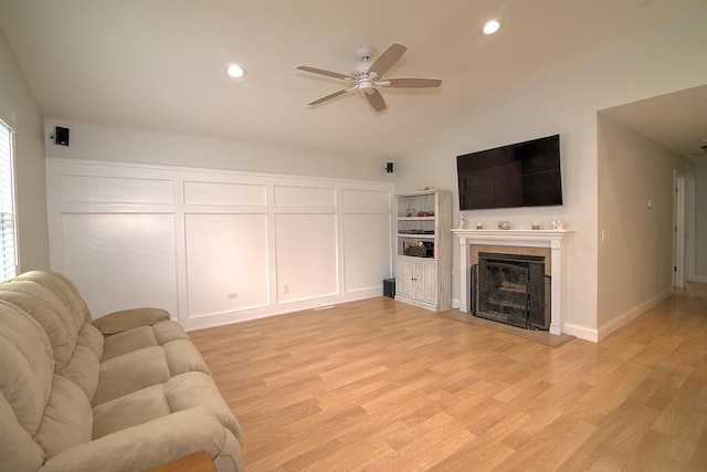 living room with lofted ceiling, a tile fireplace, recessed lighting, a ceiling fan, and light wood-style floors