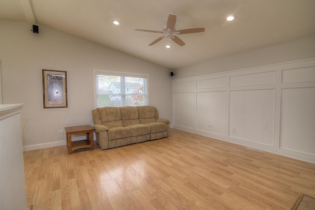 living room featuring lofted ceiling with beams, recessed lighting, a decorative wall, a ceiling fan, and light wood finished floors