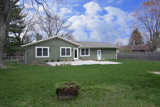 rear view of property with fence private yard, a patio area, a chimney, and a yard